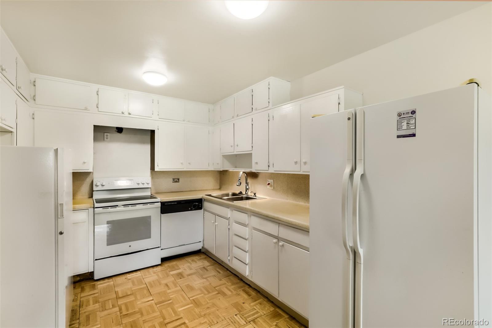 625 South Clinton Street, Unit 7B Denver, CO 80247 - Photo 3 of 22 a kitchen with white cabinets and stainless steel appliances