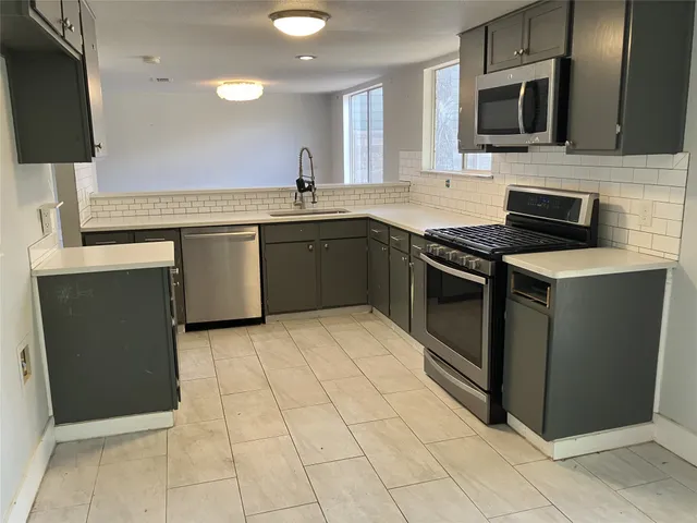 a kitchen with stainless steel appliances granite countertop a stove a sink and a microwave