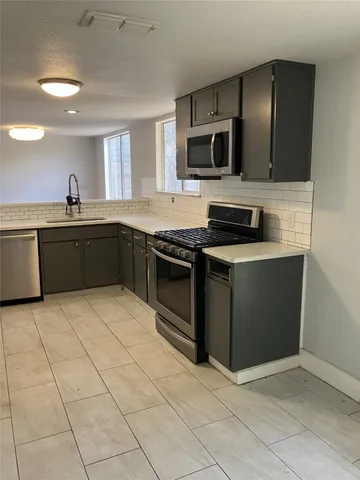 a kitchen with stainless steel appliances granite countertop a stove a sink and a microwave