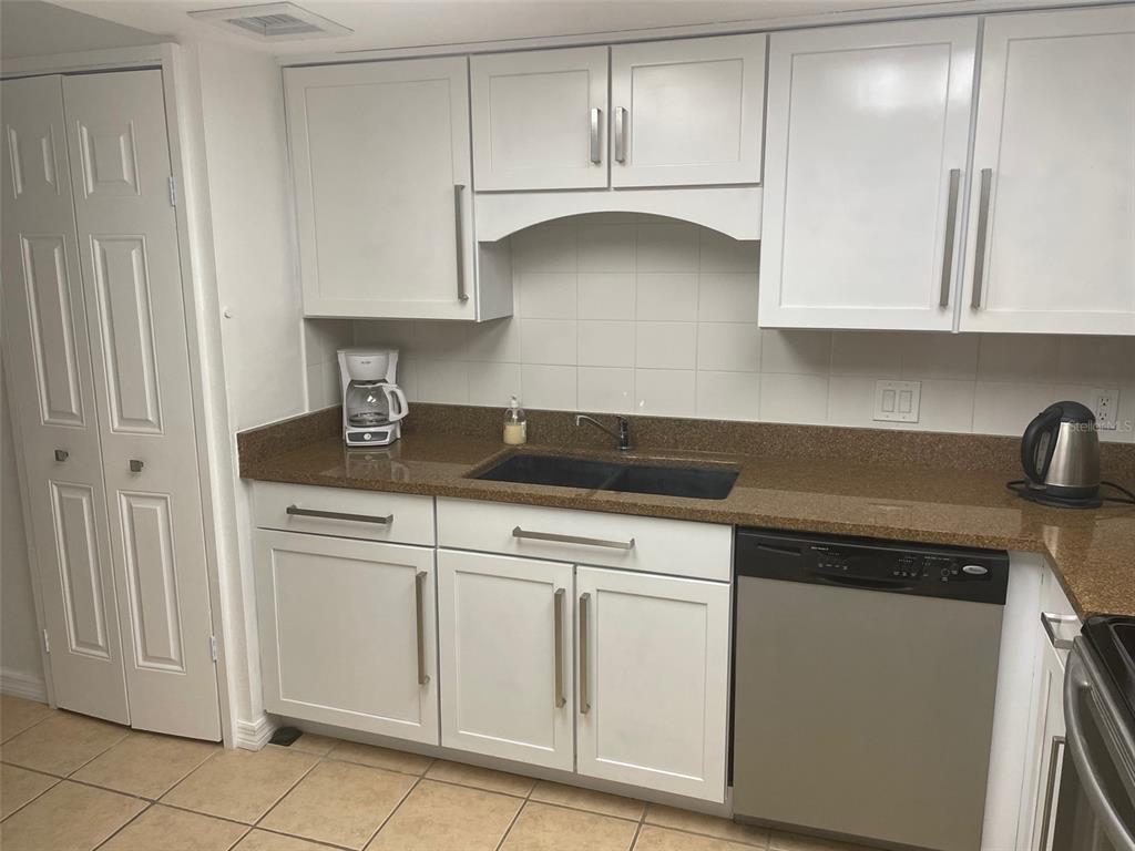 1 Key Capri, Unit 104W Treasure Island, FL 33706 - Photo 12 of 49 a kitchen with white cabinets and white appliances