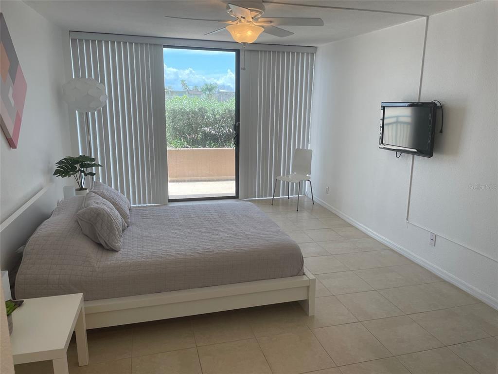 1 Key Capri, Unit 104W Treasure Island, FL 33706 - Photo 18 of 49 a bedroom with a bed and a flat tv screen on dresser