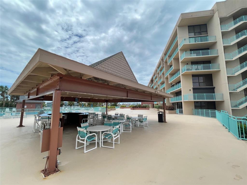 1 Key Capri, Unit 104W Treasure Island, FL 33706 - Photo 40 of 49 a view of a patio with table and chairs with wooden floor and fence