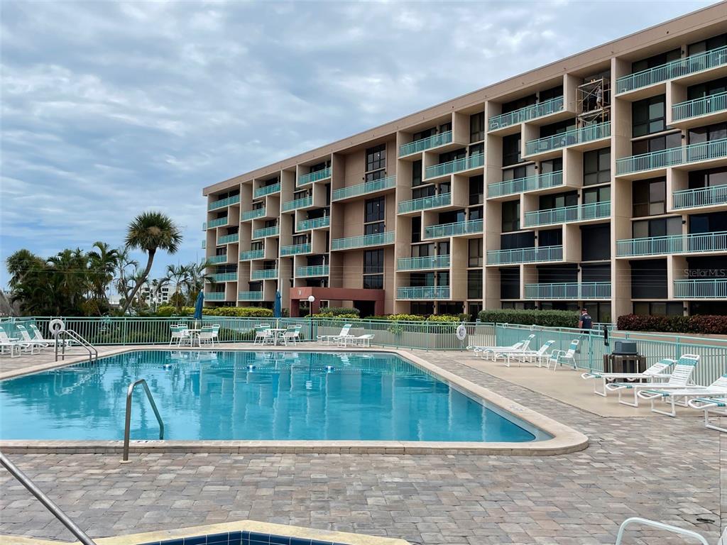 1 Key Capri, Unit 104W Treasure Island, FL 33706 - Photo 41 of 49 a view of swimming pool with outdoor seating and house in the background
