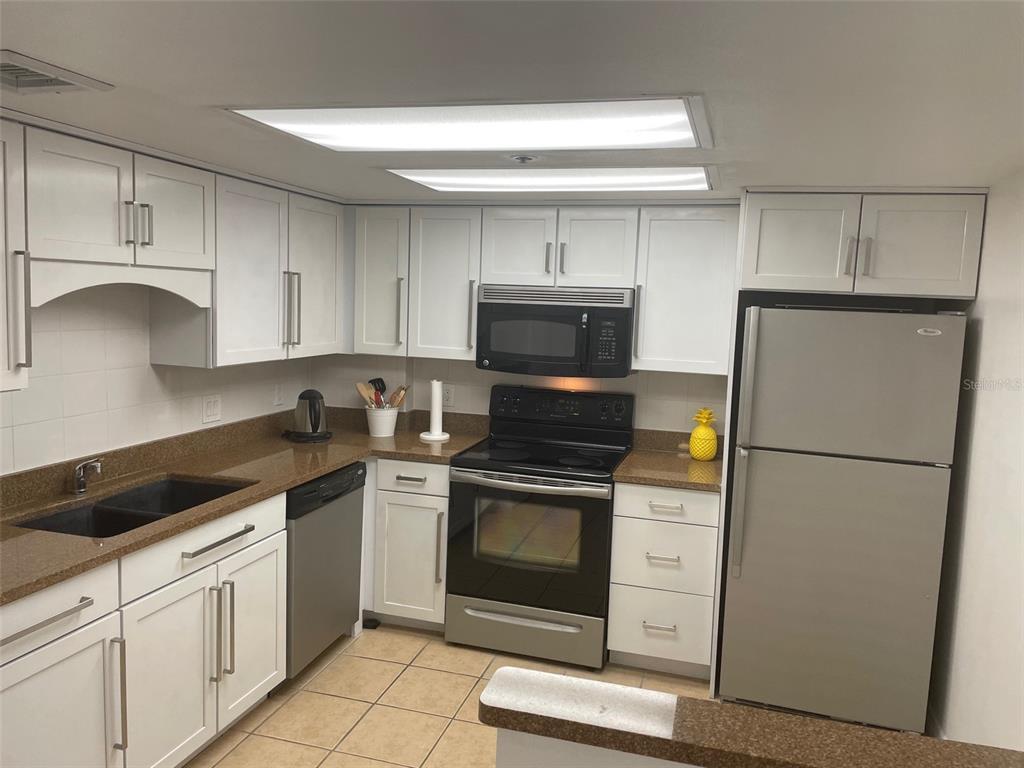 1 Key Capri, Unit 104W Treasure Island, FL 33706 - Photo 9 of 49 a kitchen with a refrigerator sink and cabinets