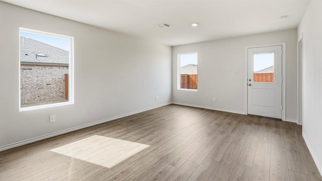 3535 Spring Time Street Forney, TX 75126 - Photo 8 of 23 Spacious room featuring wood-finish flooring, light-toned walls, multiple windows, recessed lighting, and a rear door with an integrated window