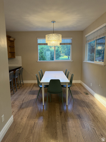 2388 East 850 South Springville, UT 84663 - Photo 9 of 24 Bright dining room showcasing wood-finish flooring, a white rectangular dining table, and a pendant light fixture suspended from the ceiling