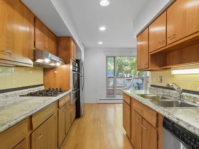 a kitchen with kitchen island granite countertop a sink stove and cabinets