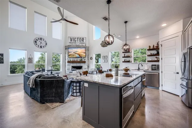 a open kitchen with stainless steel appliances granite countertop a stove and a view of living room