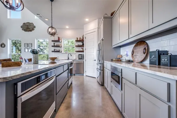 a kitchen with stainless steel appliances granite countertop a sink a stove and cabinets