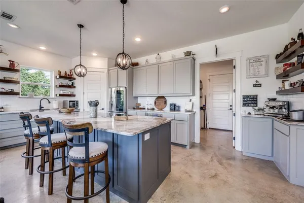 a kitchen with stainless steel appliances kitchen island a table chairs and a refrigerator