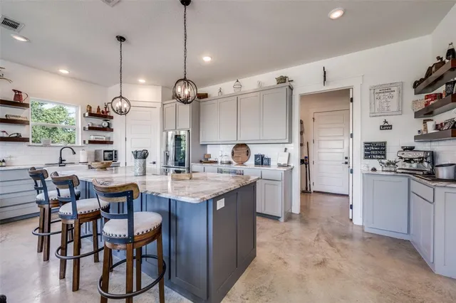 a kitchen with stainless steel appliances kitchen island a table chairs and a refrigerator