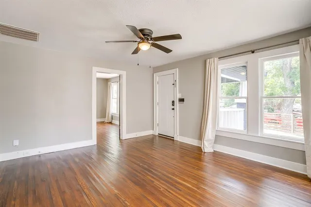 a view of an empty room with wooden floor and a window