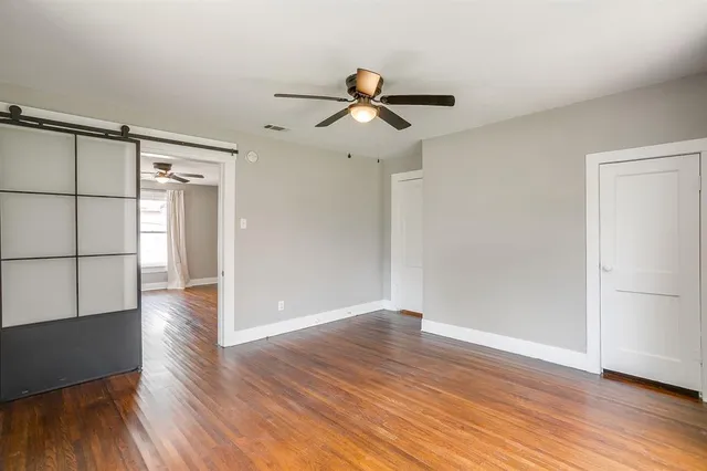 an empty room with wooden floor cabinet and windows