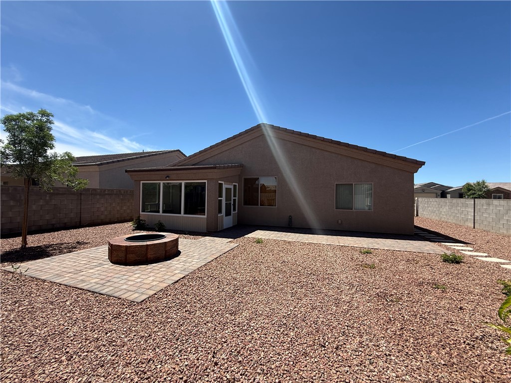 4786 East Old W Road Kingman, AZ 86401 - Photo 11 of 12 Sunroom addition featuring large windows, a paver patio with built-in fire pit, and low-maintenance gravel landscaping