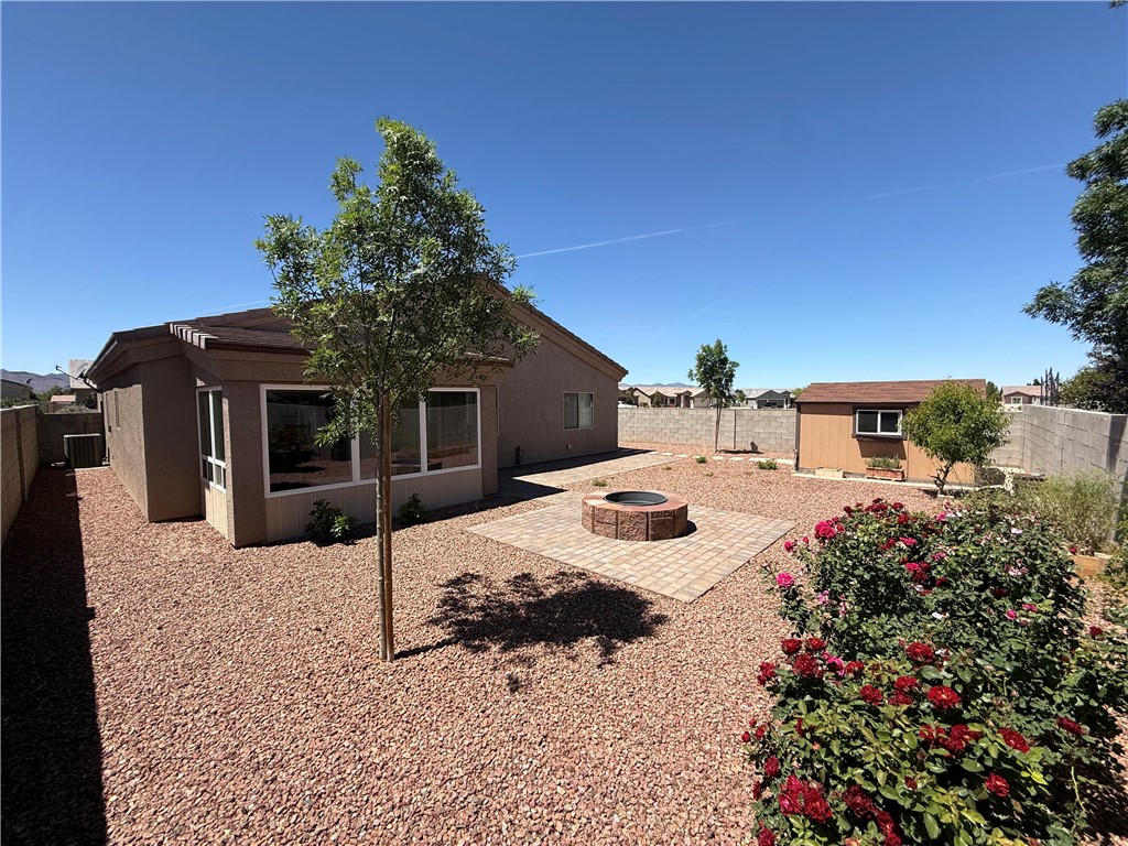 4786 East Old W Road Kingman, AZ 86401 - Photo 12 of 12 Spacious backyard featuring a built-in fire pit on a paver patio, a utility shed, and decorative gravel landscaping