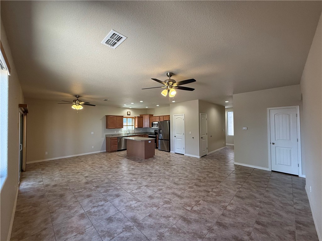 4786 East Old W Road Kingman, AZ 86401 - Photo 3 of 12 Open-concept living area featuring large format tile flooring, a kitchen with wood cabinetry and stainless steel appliances, and multiple ceiling fans with integrated lighting