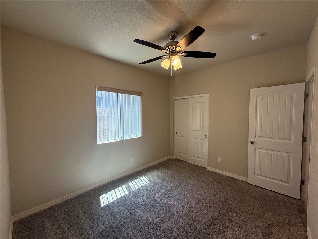 4786 East Old W Road Kingman, AZ 86401 - Photo 5 of 12 Carpeted interior space featuring a ceiling fan with integrated lighting, window with vertical blinds, and a paneled interior door