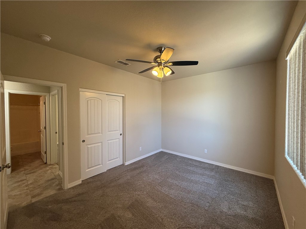 4786 East Old W Road Kingman, AZ 86401 - Photo 6 of 12 Carpeted room with a ceiling fan with integrated lighting, a window with vertical blinds, and a built-in closet with sliding panel doors
