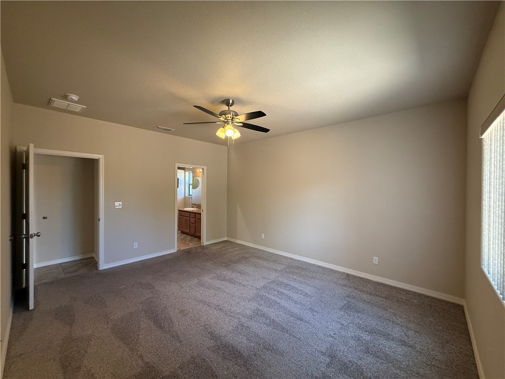 4786 East Old W Road Kingman, AZ 86401 - Photo 8 of 12 Spacious room featuring vaulted ceilings, neutral carpet flooring, a ceiling fan with integrated lighting, and vertical blinds