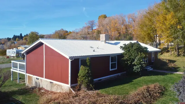 a view of a house with a yard and large tree
