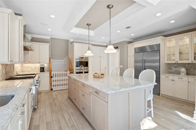 a large white kitchen with a stove top oven a sink a counter space and living room view