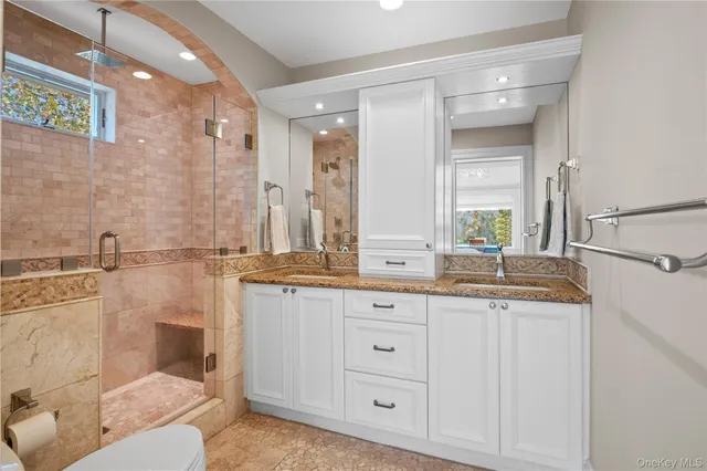 a bathroom with a granite countertop sink a toilet a mirror and shower