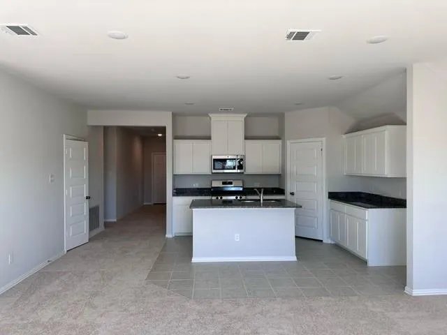 a kitchen with stainless steel appliances a sink a stove a refrigerator a white cabinets and wooden floor
