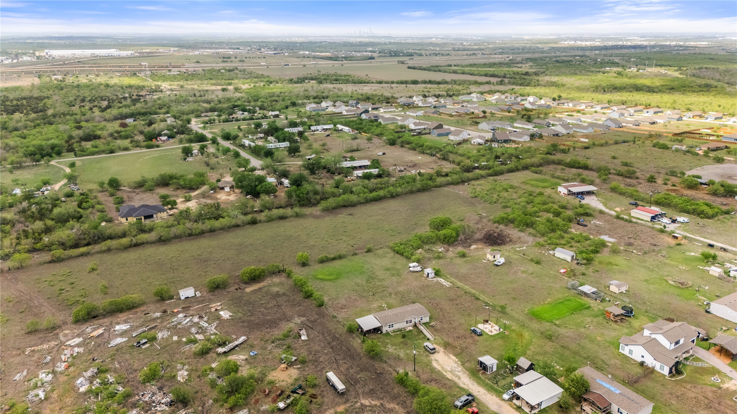 8802 Evelyn Road Buda, TX 78610 - Photo 8 of 13 Expansive aerial showcasing a large land parcel with scattered structures and residential developments in the background