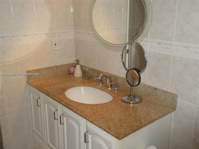 a bathroom with a granite countertop sink and a mirror