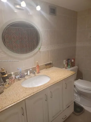 a bathroom with a granite countertop sink a toilet and a mirror