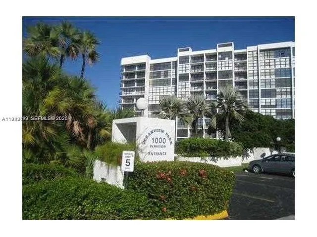 a front view of a building with windows and palm trees