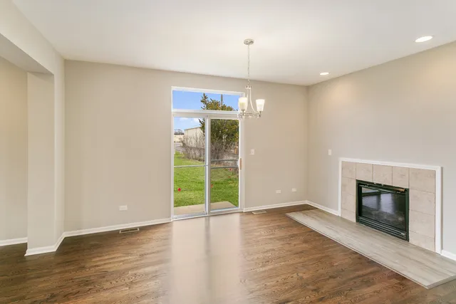 an empty room with wooden floor fireplace and windows