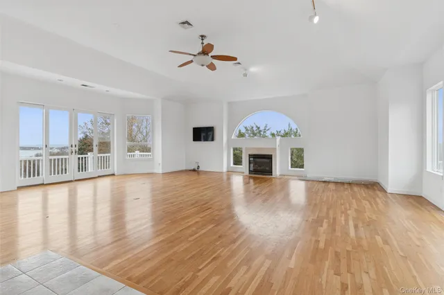 a view of an empty room with window and wooden floor