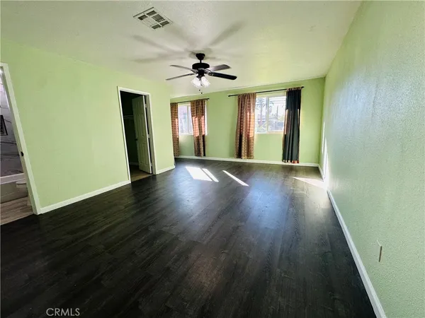 a view of an empty room with window and wooden floor