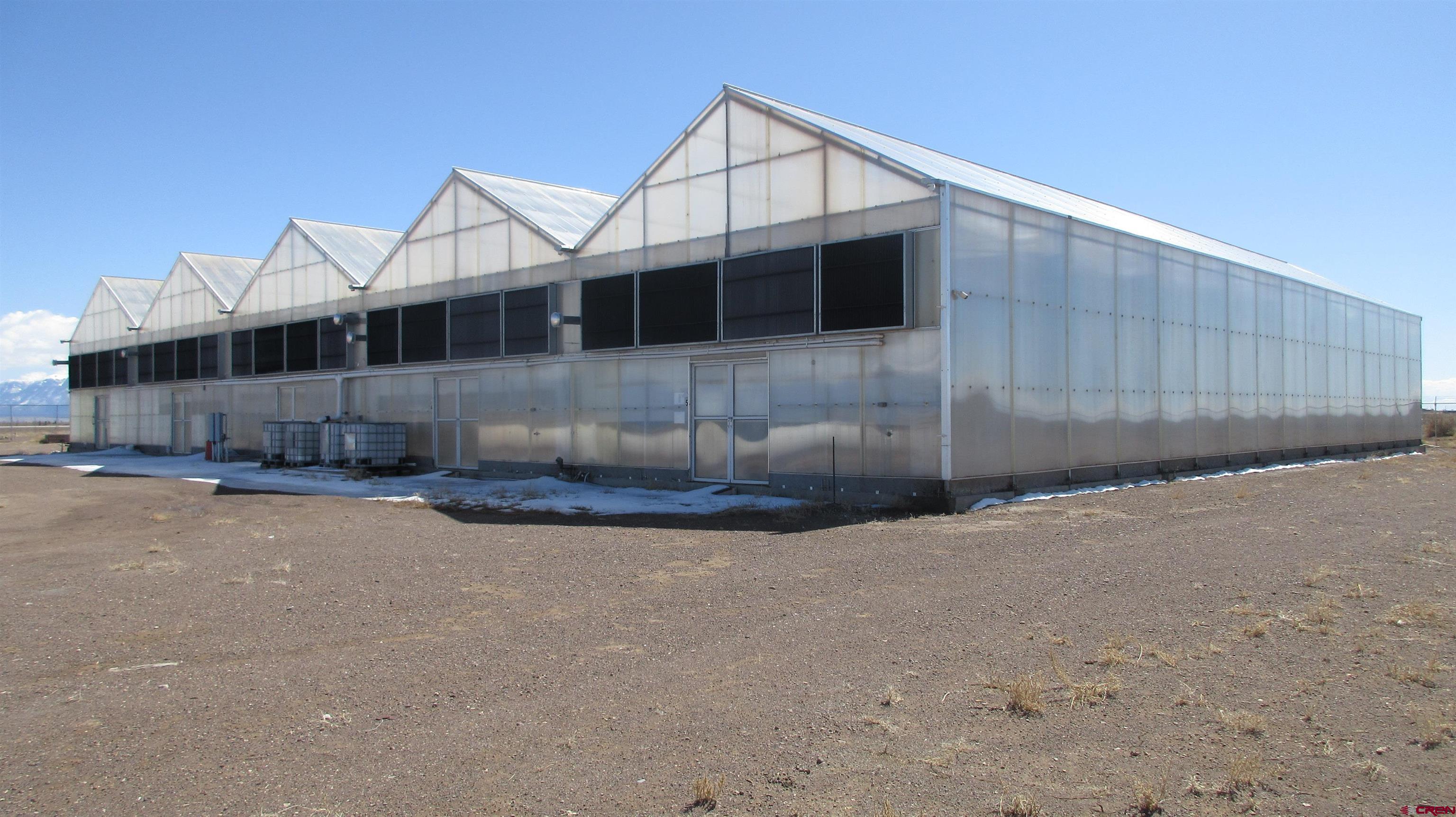 61401 County Road B Center, CO 81125 - Photo 6 of 8 a view of a large white house with a large parking space and wooden fence