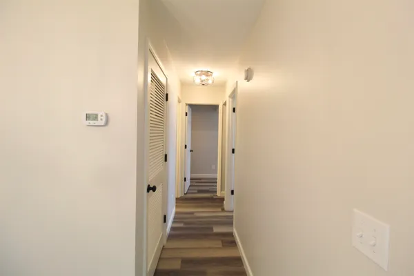 a view of a hallway with wooden floor and a bathroom