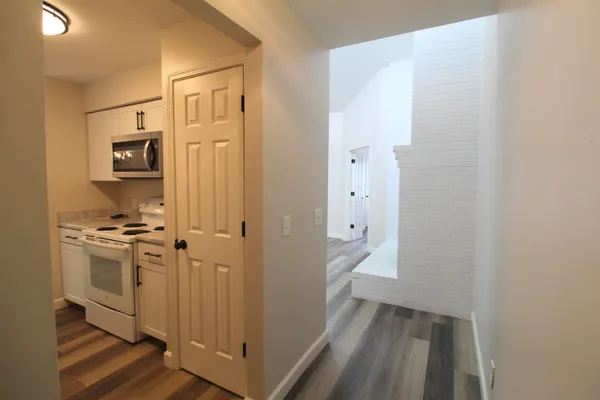 a view of a hallway with wooden floor and a bathroom