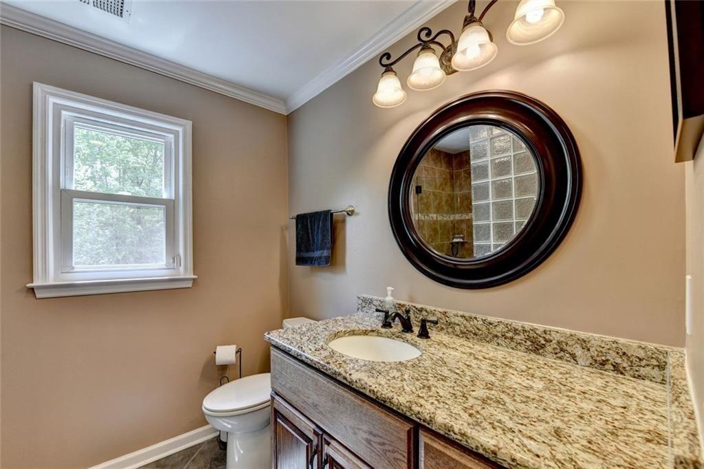 3310 Danielle Way Suwanee, GA 30024 - Photo 18 of 31 a bathroom with a granite countertop toilet a sink and a mirror