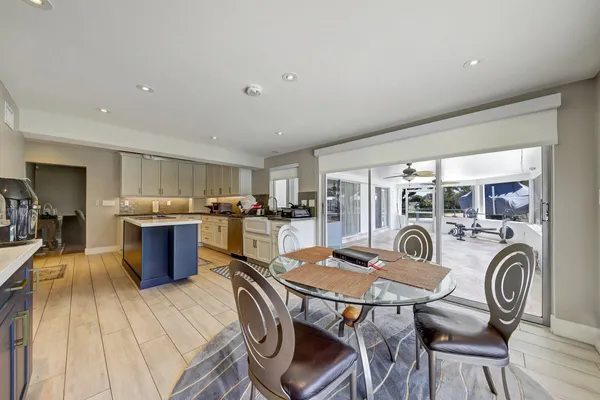 a open kitchen with stainless steel appliances granite countertop a stove top oven a sink dishwasher a dining table and chairs with wooden floor