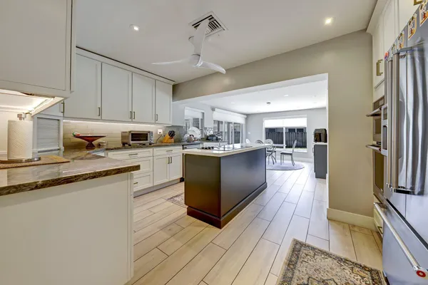 a kitchen with stainless steel appliances granite countertop a stove top oven a refrigerator a sink and dishwasher with wooden floor