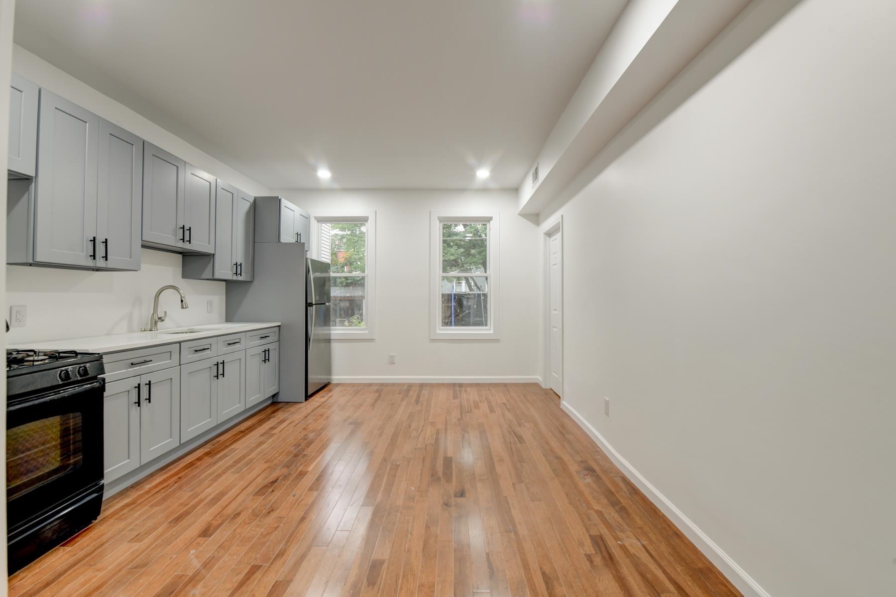 a kitchen with wooden floors and white cabinets