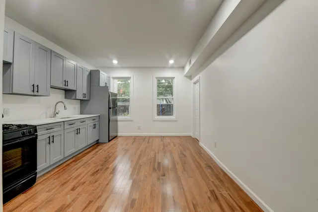 a kitchen with wooden floors and white cabinets