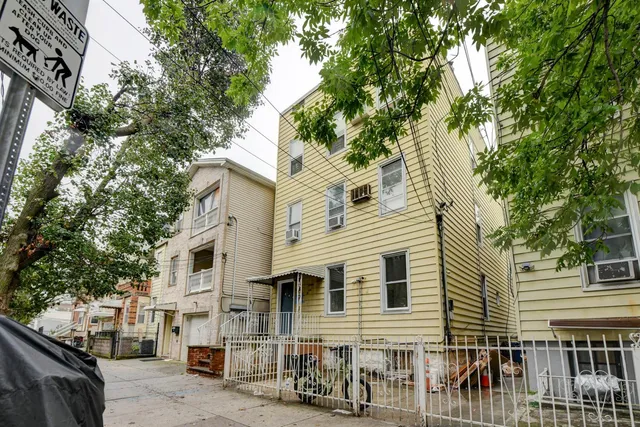 a view of a white house with large windows and a tree