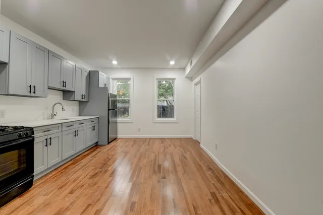 a kitchen with wooden floors and white cabinets