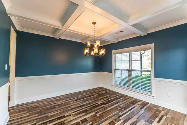 a view of an empty room with wooden floor and windows