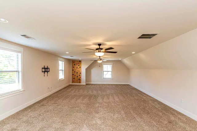 an empty room with windows and chandelier fan