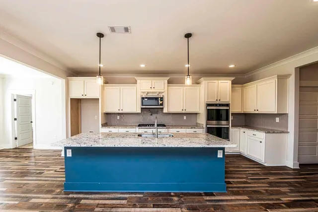 a kitchen with kitchen island granite countertop a sink cabinets and stainless steel appliances