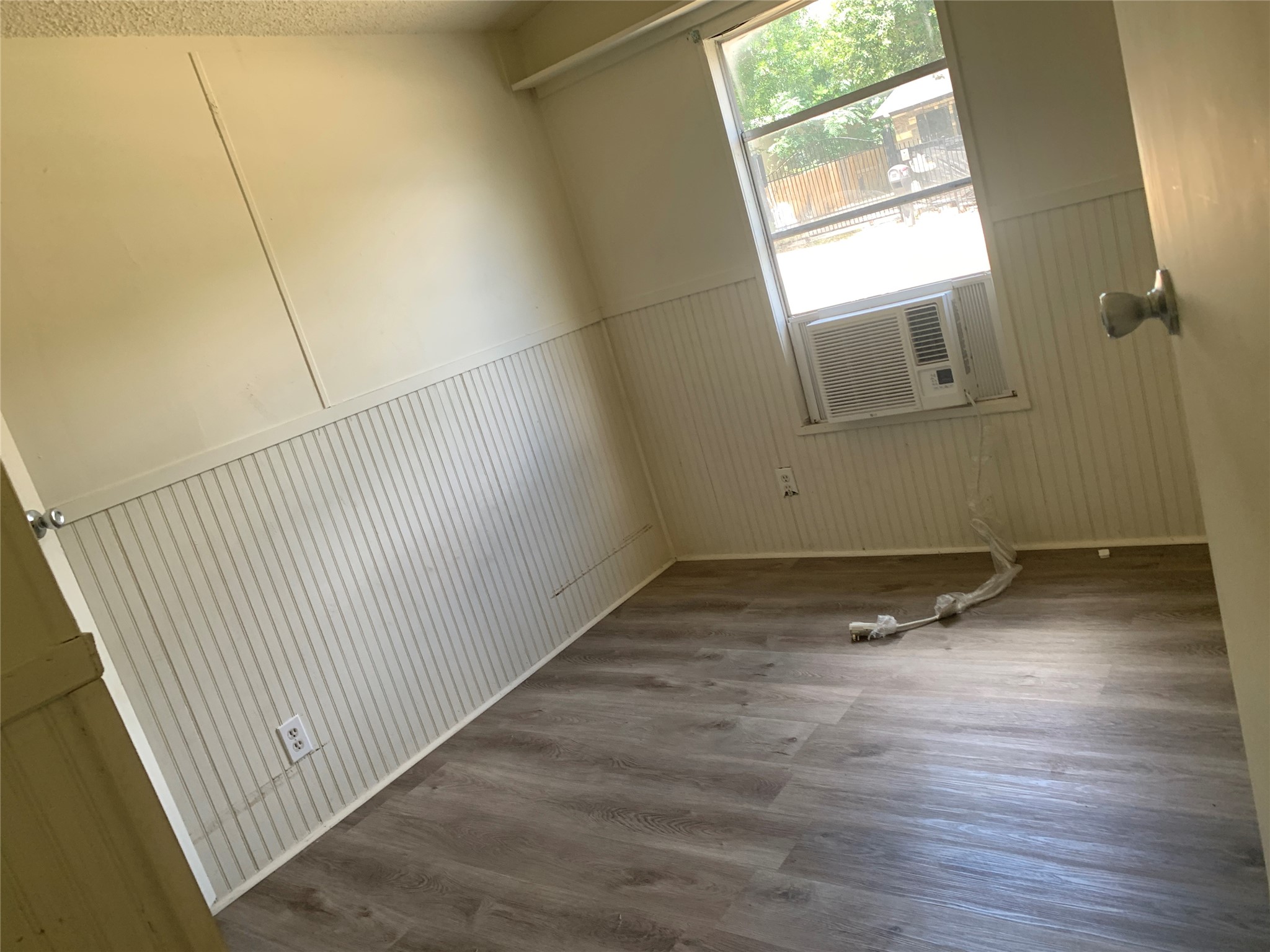 9903 Cheryl Lynn Road Austin, TX 78747 - Photo 12 of 13 A well-lit room showcasing sturdy beadboard paneling and newly installed flooring.