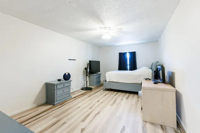 a bedroom with a bed and a flat tv screen on dresser
