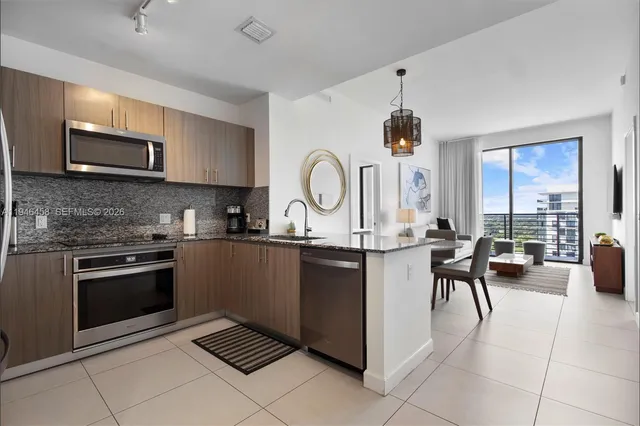 a open kitchen with stainless steel appliances granite countertop a stove top oven a sink dishwasher a dining table and chairs with wooden floor